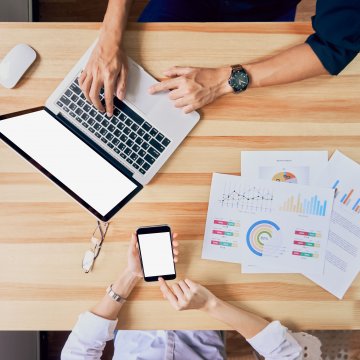Hands working on a laptop on a desk.